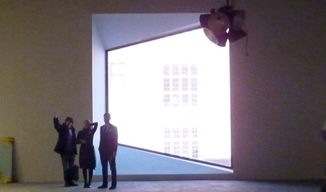 Three figures are silhouetted by a large window in the shape of a parallelogram