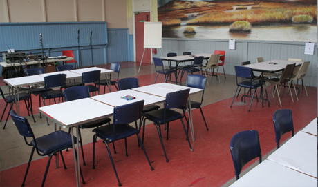 Several tables covered in white paper have blue chairs around them.