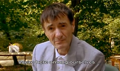 A man in garden looks at the screen - "We're here among ourselves…"