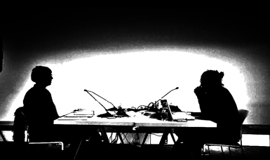 A B&W image of two people silhouetted as they sit at a table