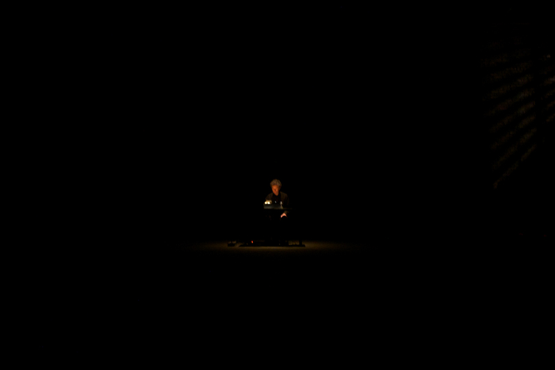 a very dark picture with a tiny dot of a person lit by a lamp in the centre