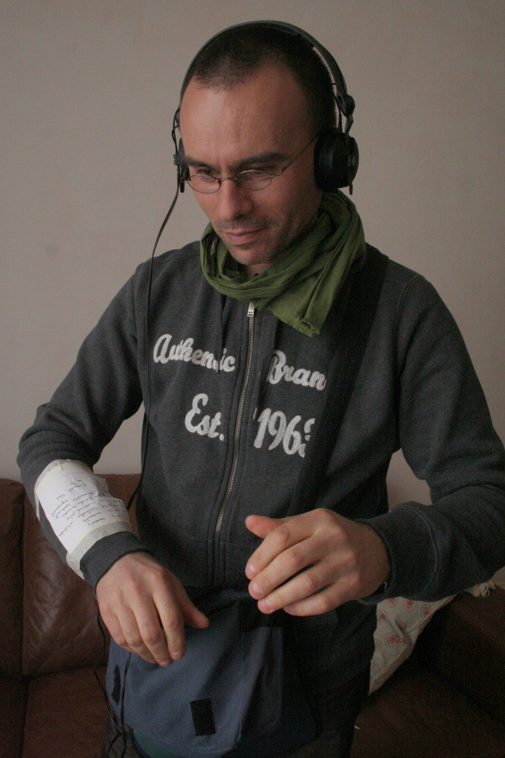 Man with headphones and sound gear looks at a score taped to his wrist