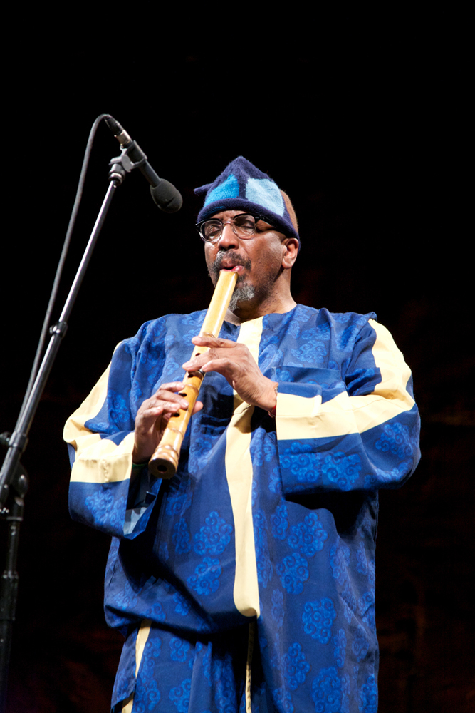 William Parker dressed in blue plays a bamboo flute