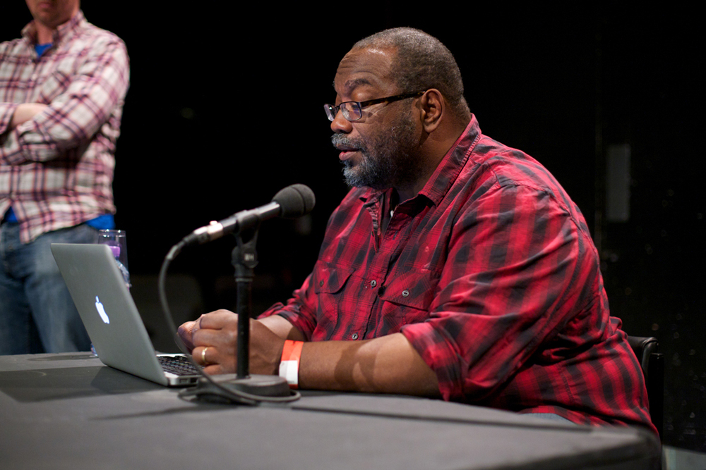 Fred Moten in a black and red shirt prepares for a discussion