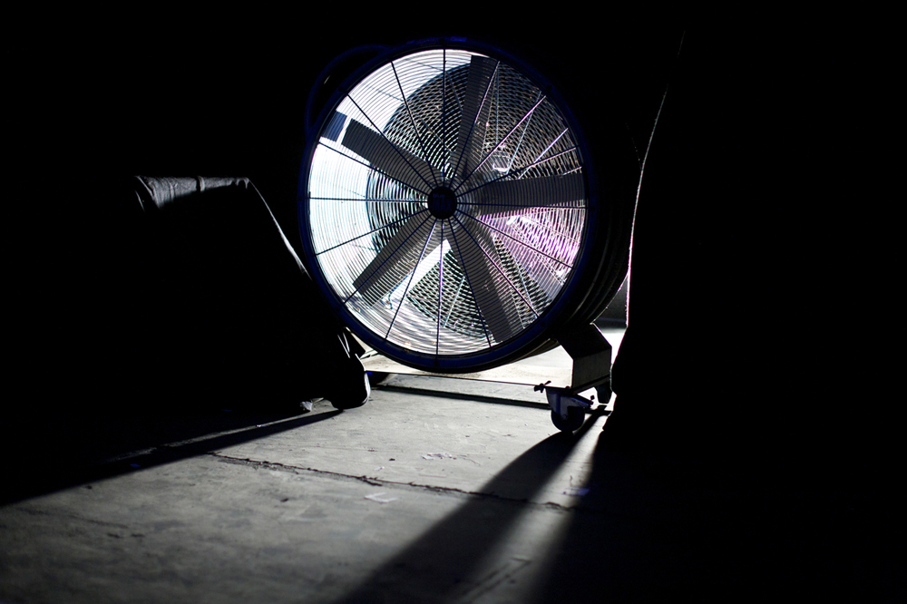 A large industrial fan is backlit