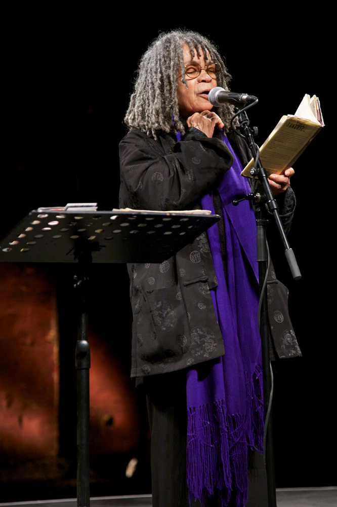 Sonia Sanchez clenches her hand to her face with closed eyes as she reads poetry