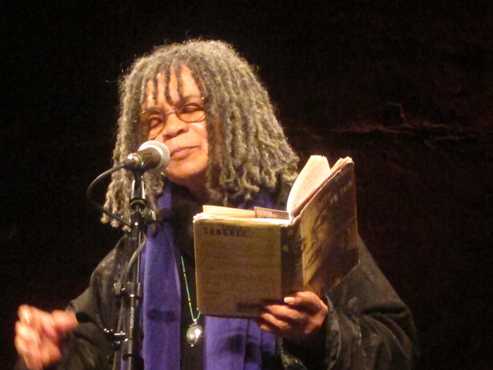 Sonia Sanchez has her closed eyes as she reads poetry whilst holding a book