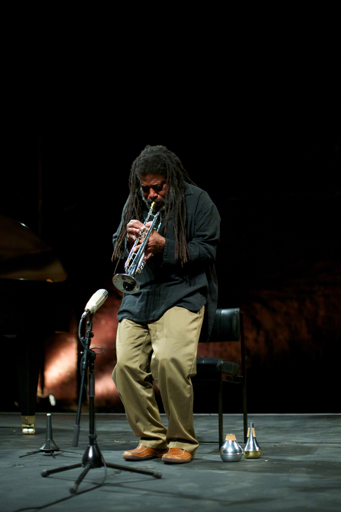 Wadada Leo Smith bends his knees as he plays trumpet