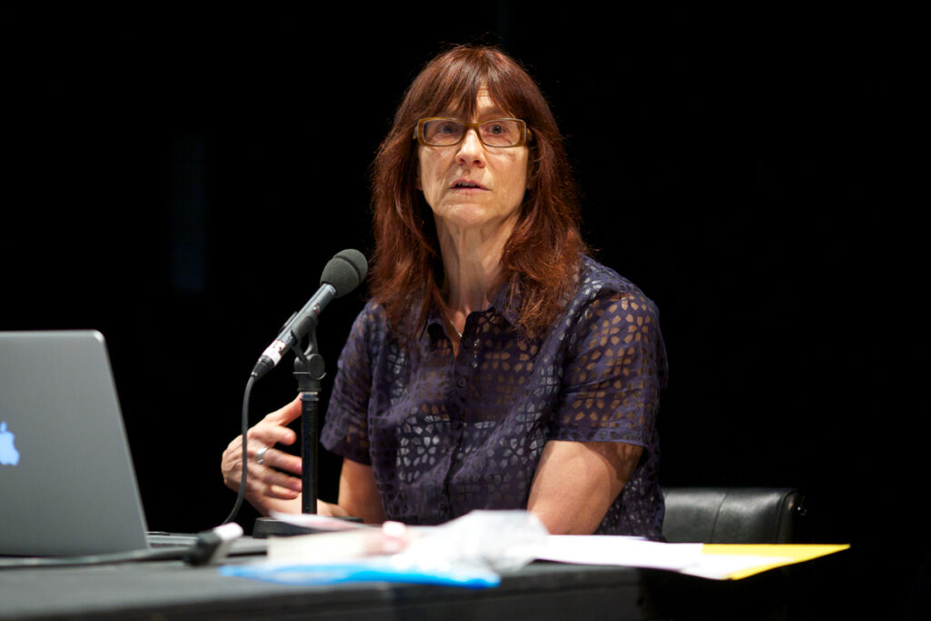 Ann Cvetkovich sitting at a table speaking into a microphone