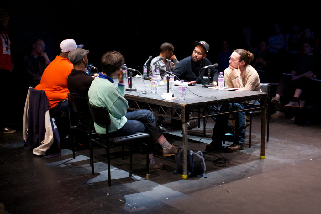 The panel members at a rectangular table listen to a question
