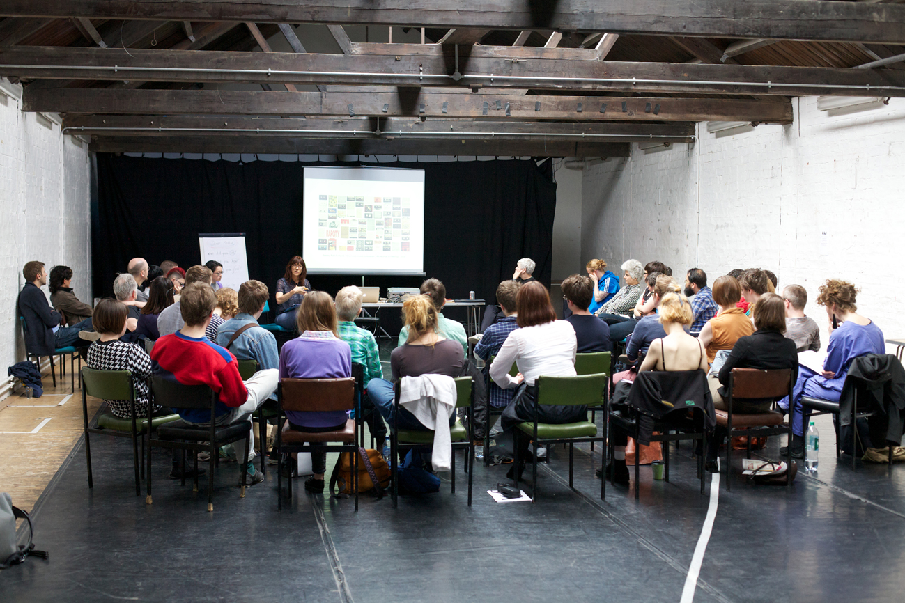 A long shot of the audience taking part in a discussion in a naturally lit room