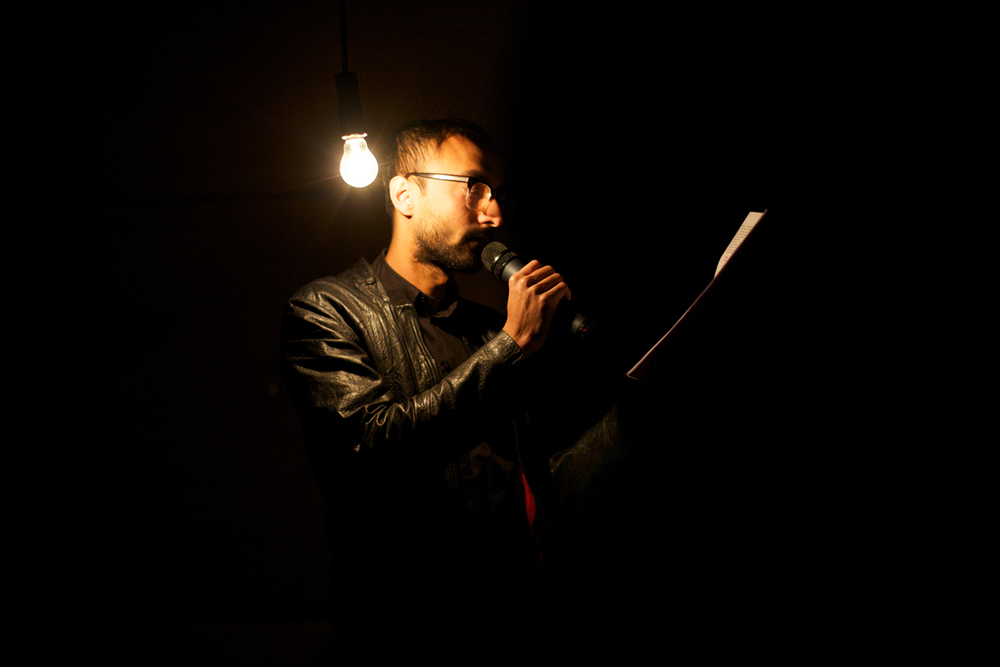 Nabil Ahmed reads by the light of a bare bulb
