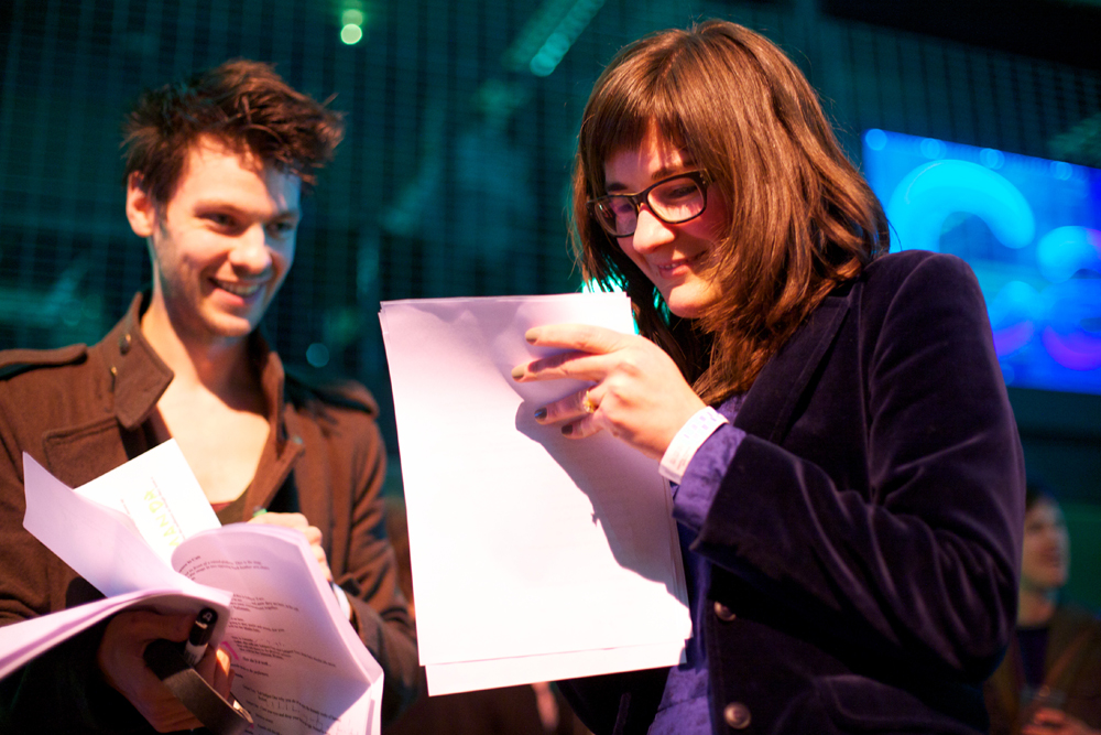 Amanda Monfroe and Iain Campbell smile as they look at a script