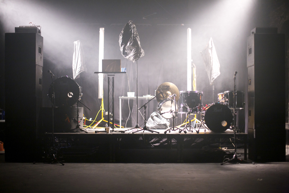 A stage set with vertical lights, fog, speakers and a mic covered with a bag
