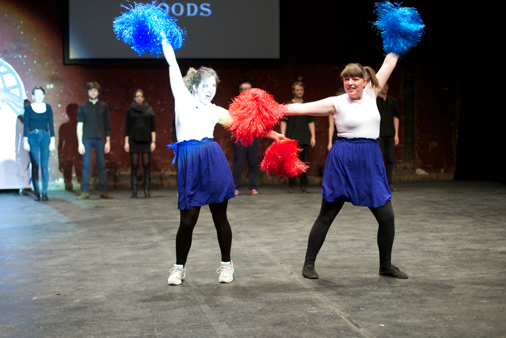 Two cheerleader type characters dance enthusiastically with pompoms