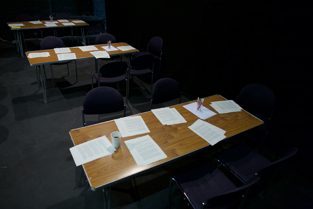 Tables set out with papers in a dark room in preparation for a workshop