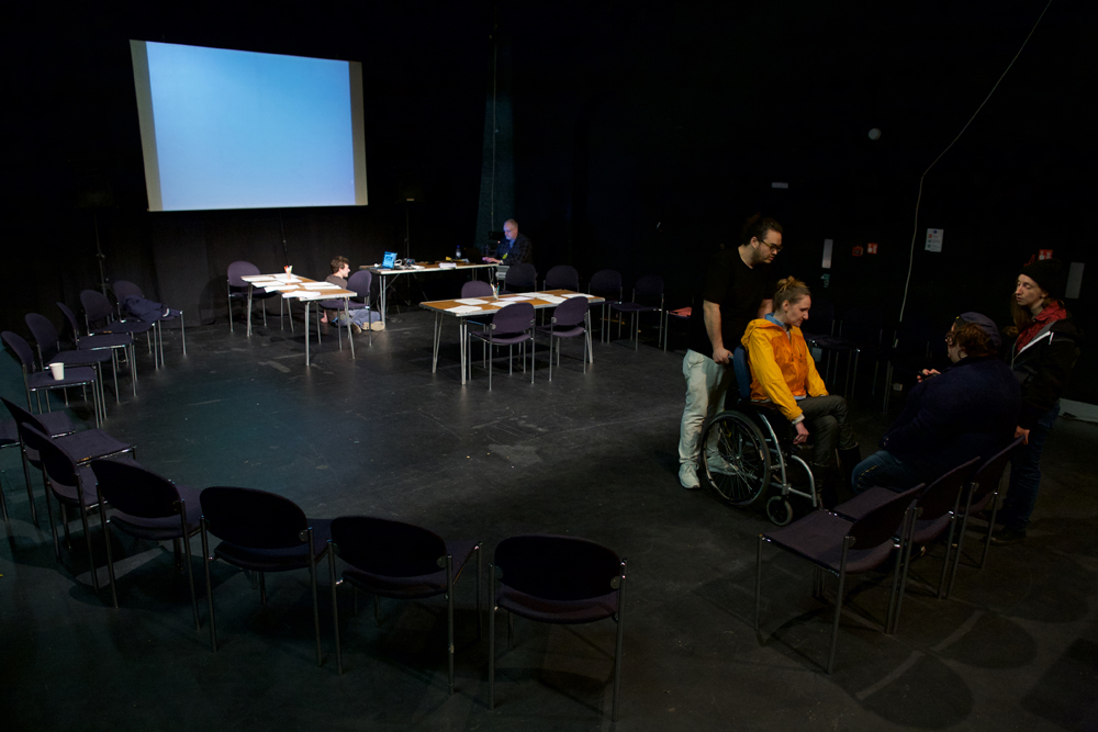 A dark room is set out with a screen and chairs in preparation for a workshop