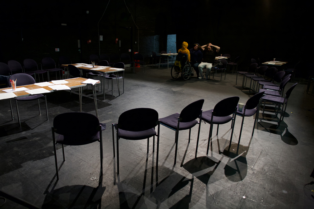 A dark room is set out with tables and chairs in preparation for a workshop