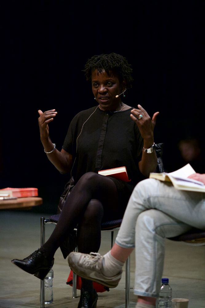 Denise Fererria Da Silva holds both hands in the air as she talks to the group