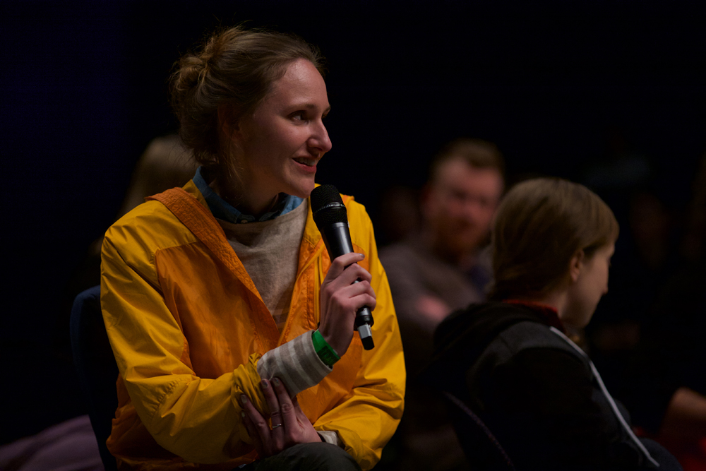 Park McCarthur in a yellow jacket asks a question to the group