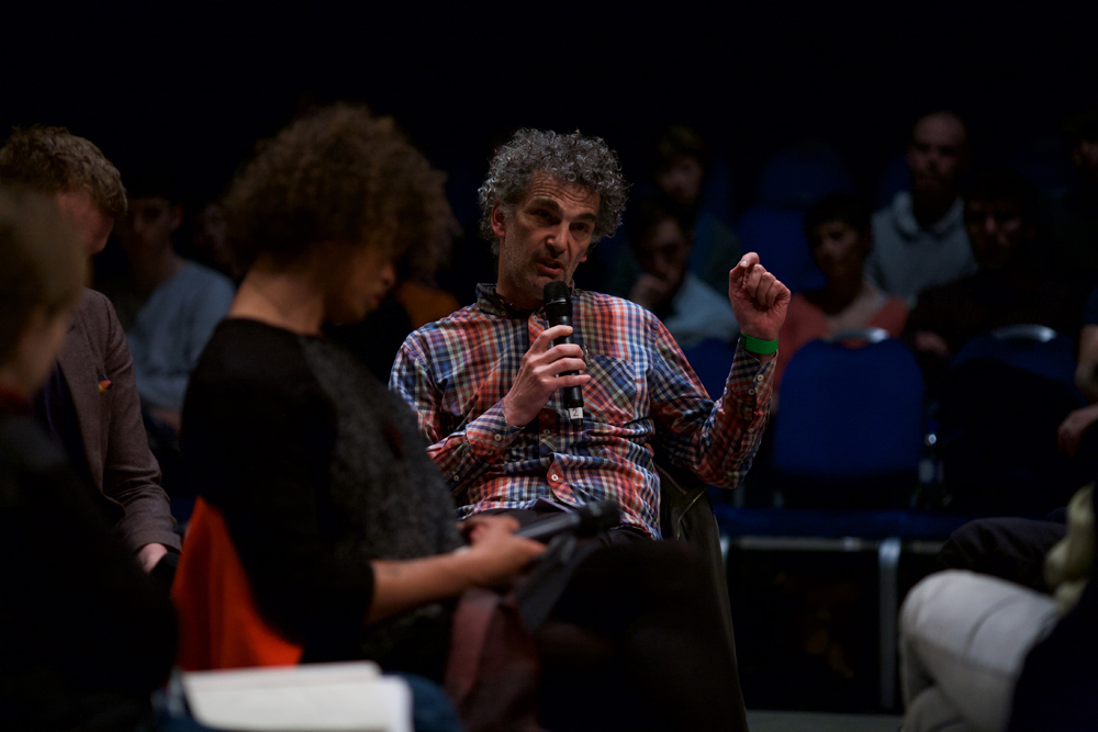 Howard Slater in a checked shirt asks a question to the group