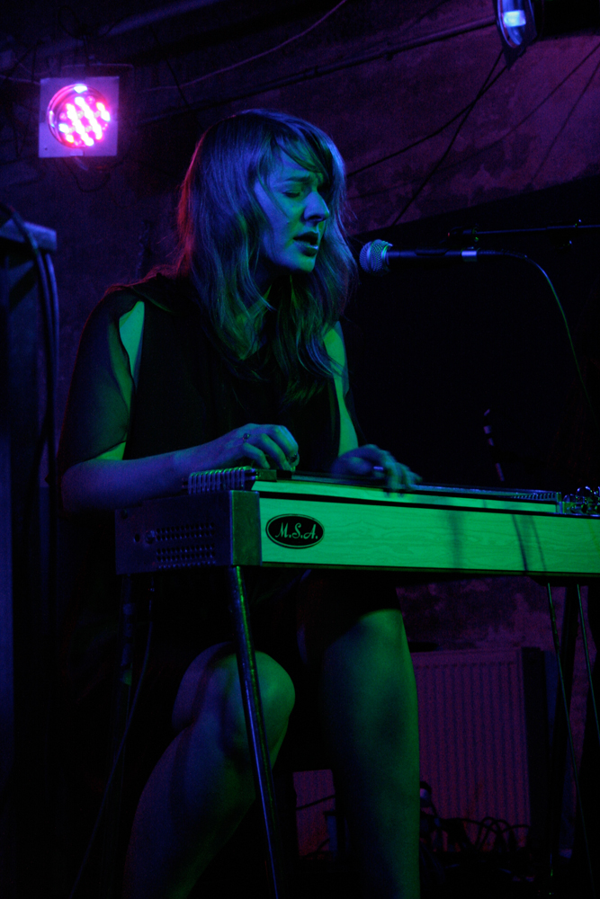 Heather Leigh Murray plays lap steel guitar and sings by green and pink light