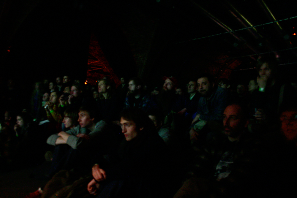An audience watch the performance in a dark space