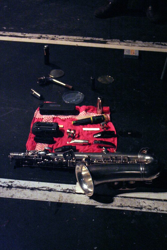An alto saxophone lying on a red cloth along with various small objects