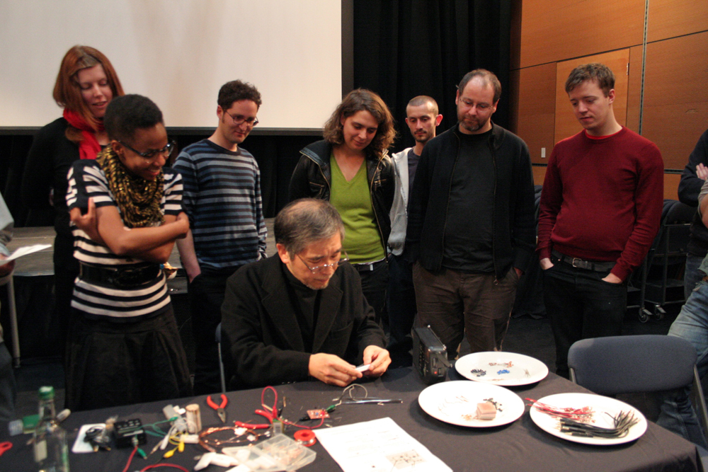 A group gather as Tetsuo Kogawa shows folks how to make a radio