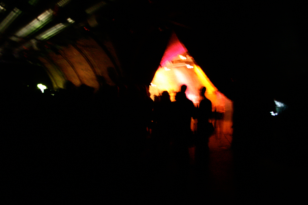 A dark room with a milling audience