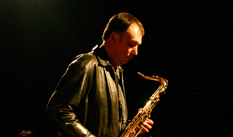 John Butcher holds and plays a saxophone