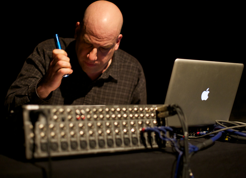 A man with a torch looking at a mixing board