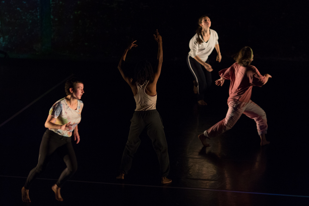 A group of people on a stage, they move quickly. One has their hands in the air