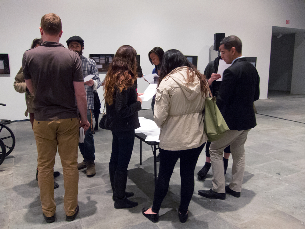 A group of people gather at a table looking at bits of paper