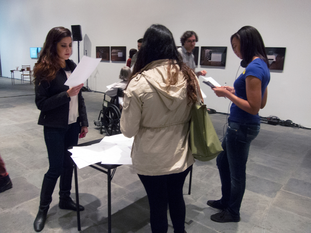 A group of people gather at a table looking at bits of paper