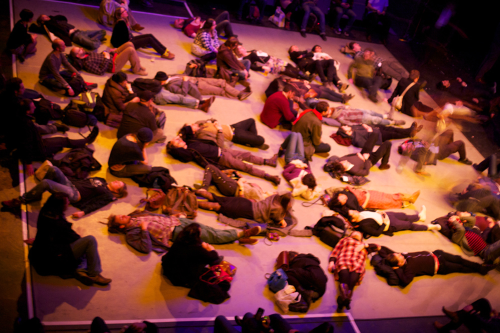 audience members are scattered lying on a floor, taken from above
