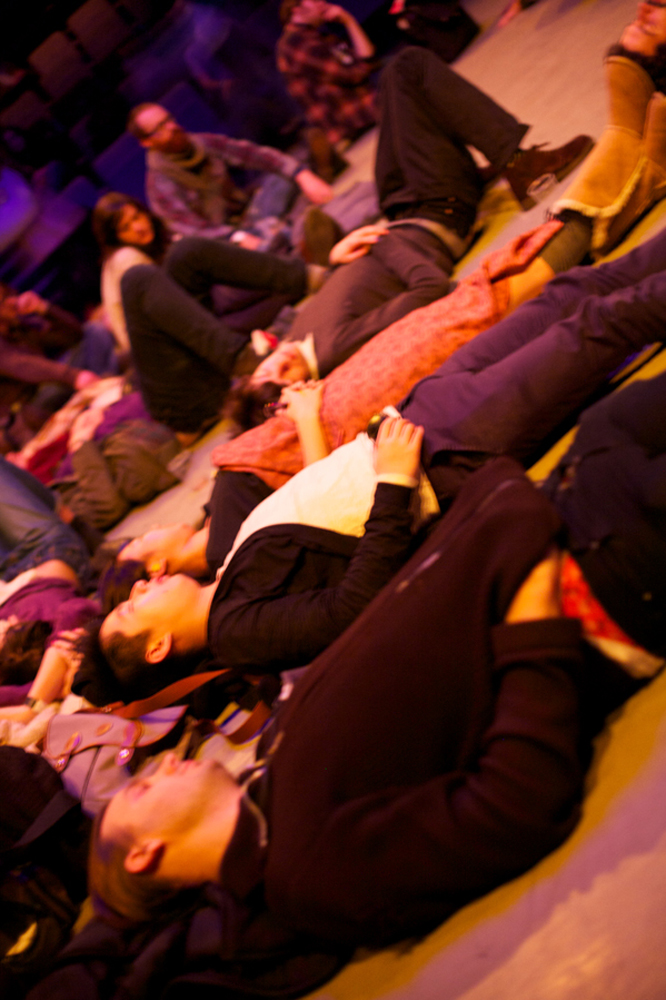 audience members are scattered lying on a floor, taken from an angle