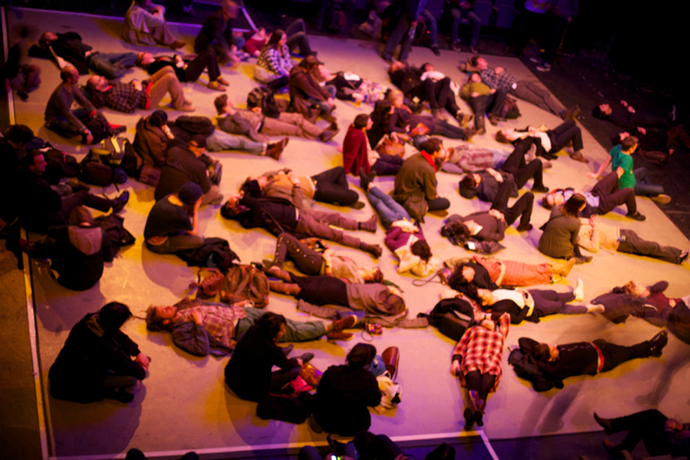 audience members are scattered lying on a floor, taken from above
