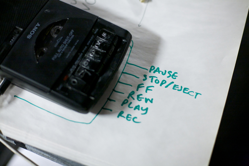 A tape recorder on a piece of paper that reads play, stop, pause and record
