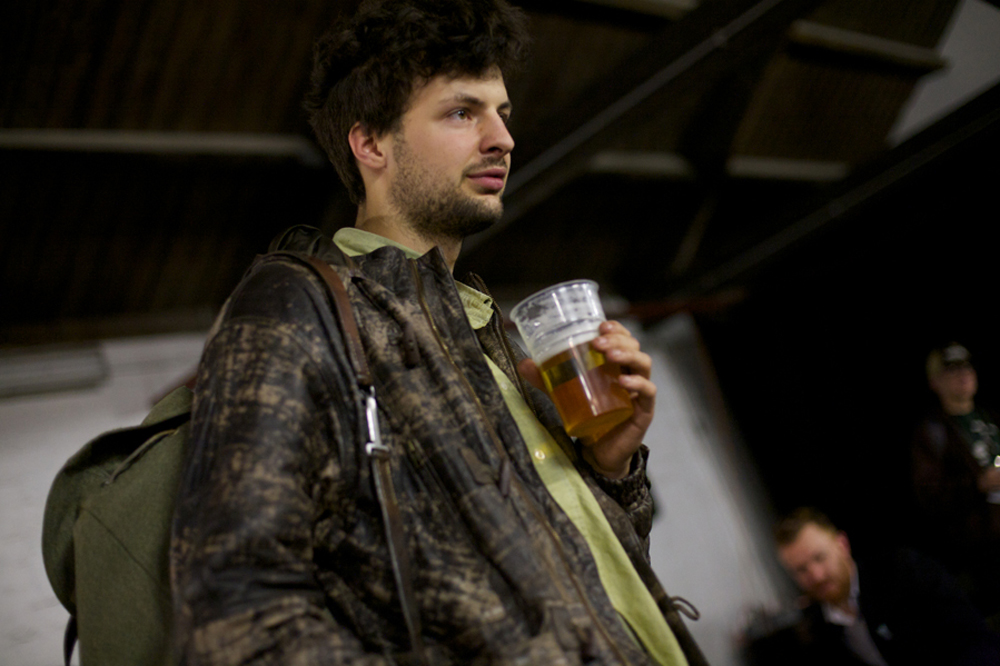 A man looks out of frame as he holds a pint of beer