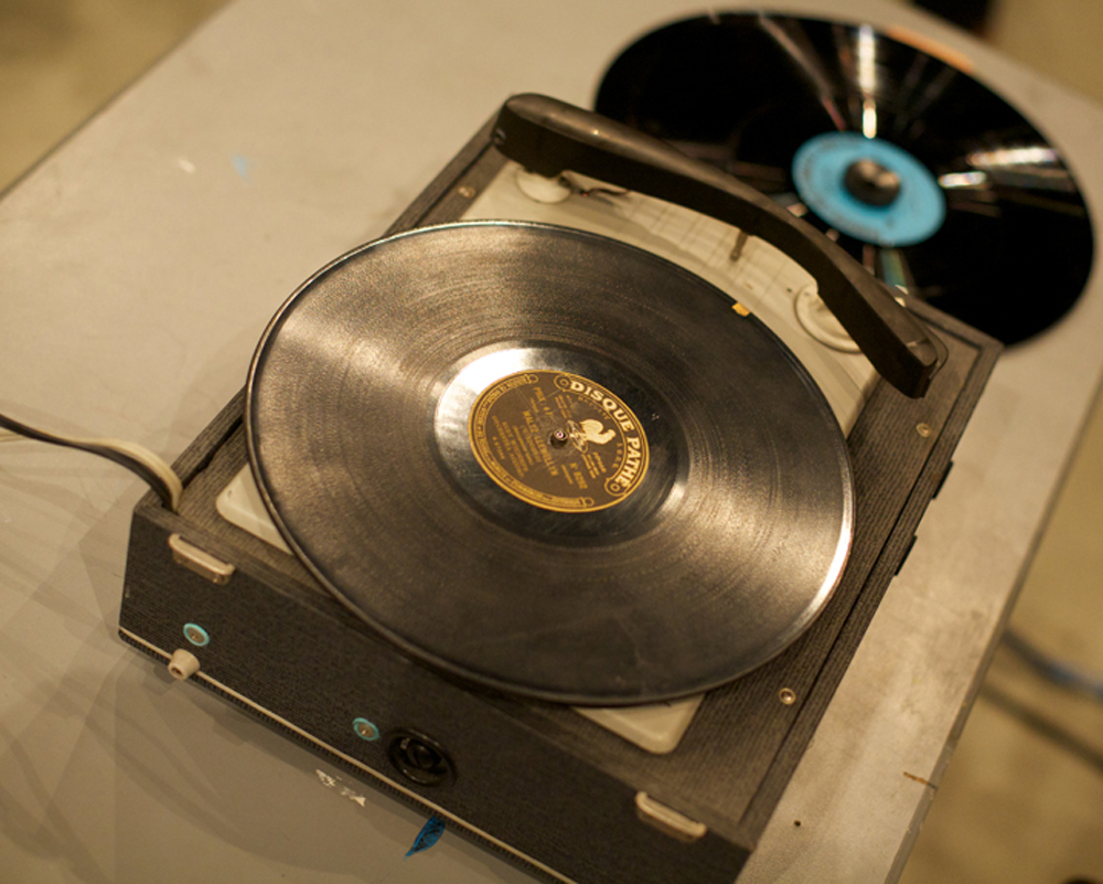 A record deck with an old record on another record with a blue label to the side