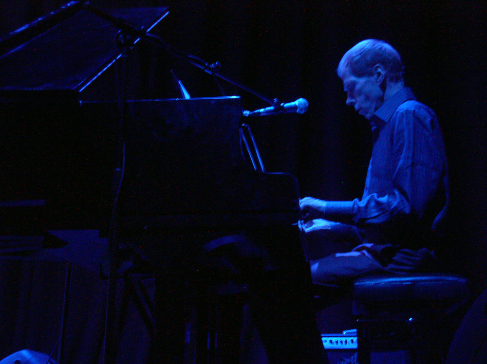 A man playing a piano in blue light