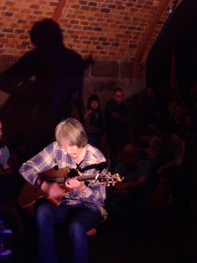 Man playing guitar in an arched room with light from below