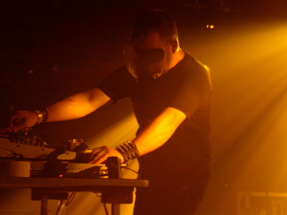 A man in a cat mask operates musical equipment