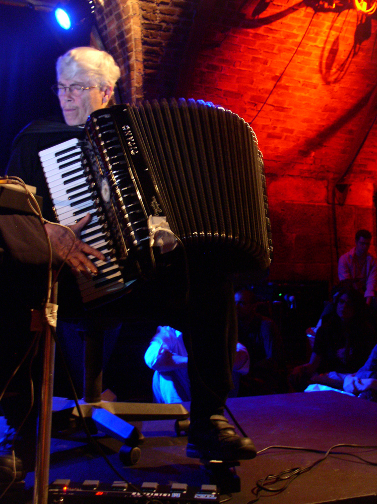 Pauline Oliveros playing an accordion whilst operating a foot pedal