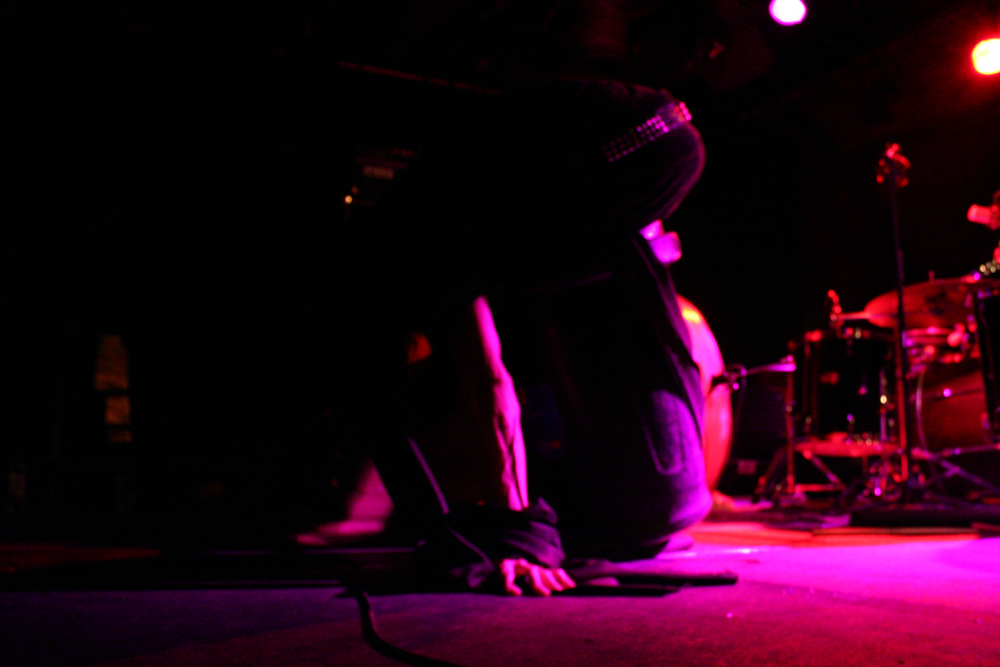 A contorted bass player invisible except for hands and belt