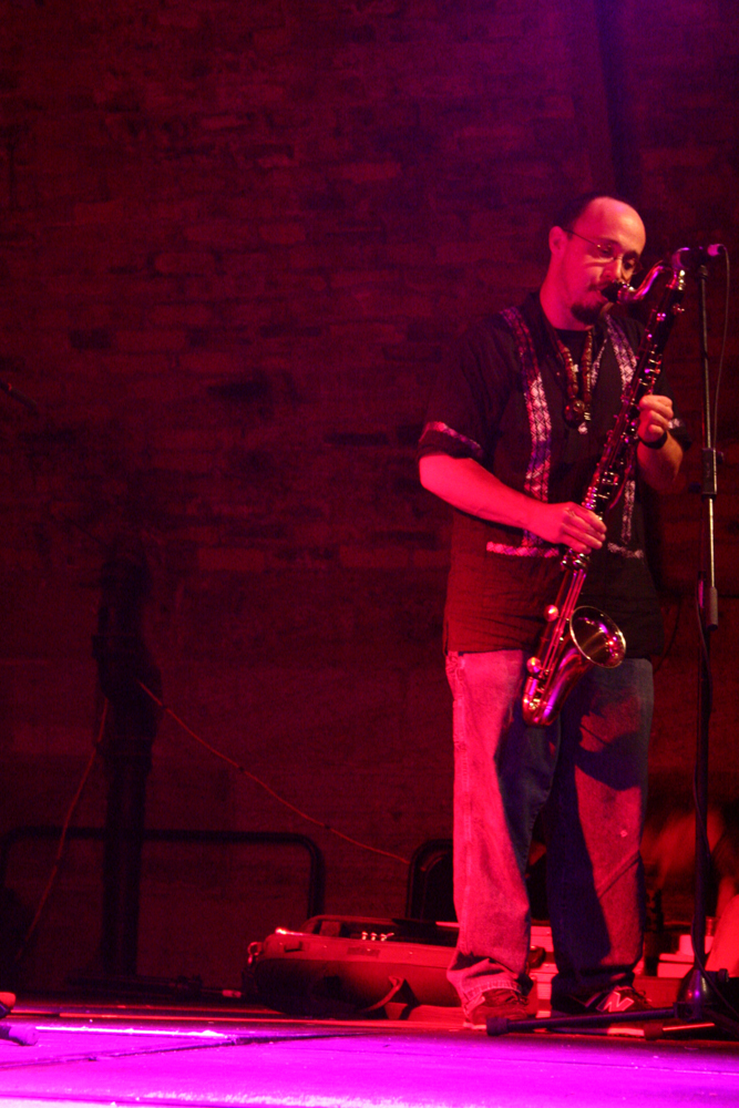 A man playing bass clarinet lit  in purple light
