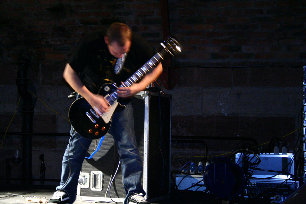 Guitar player in front of a large amplifier