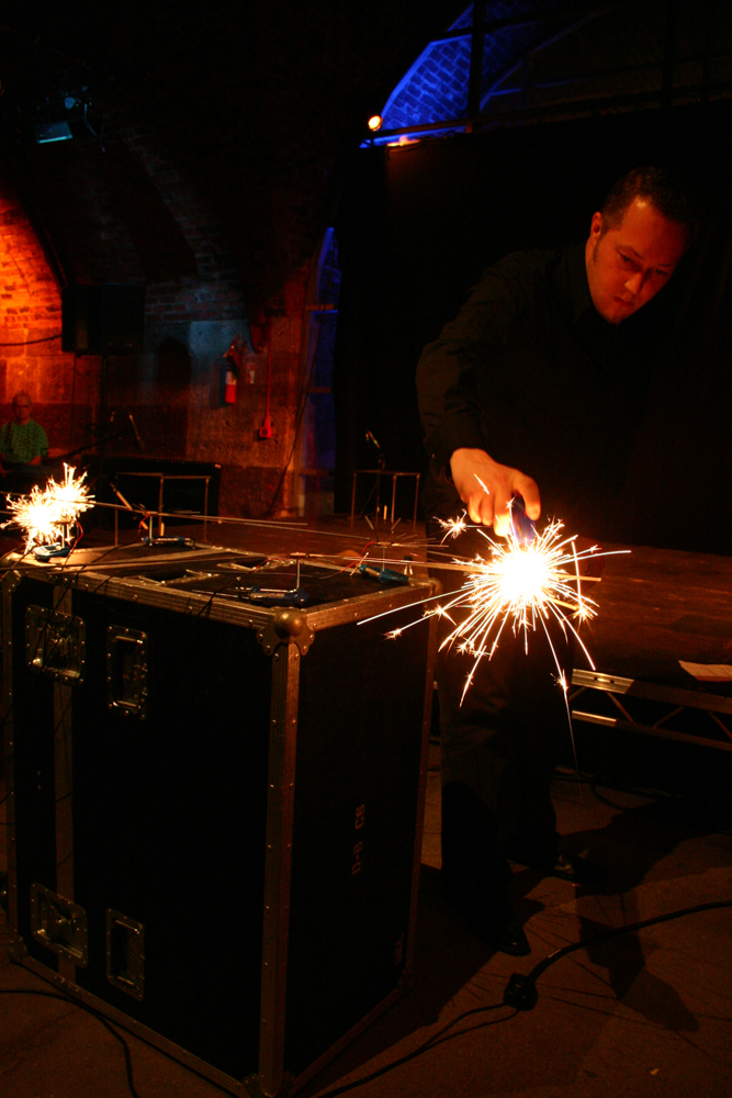 A man sets light to a sparkler firework mounted on a metal frame