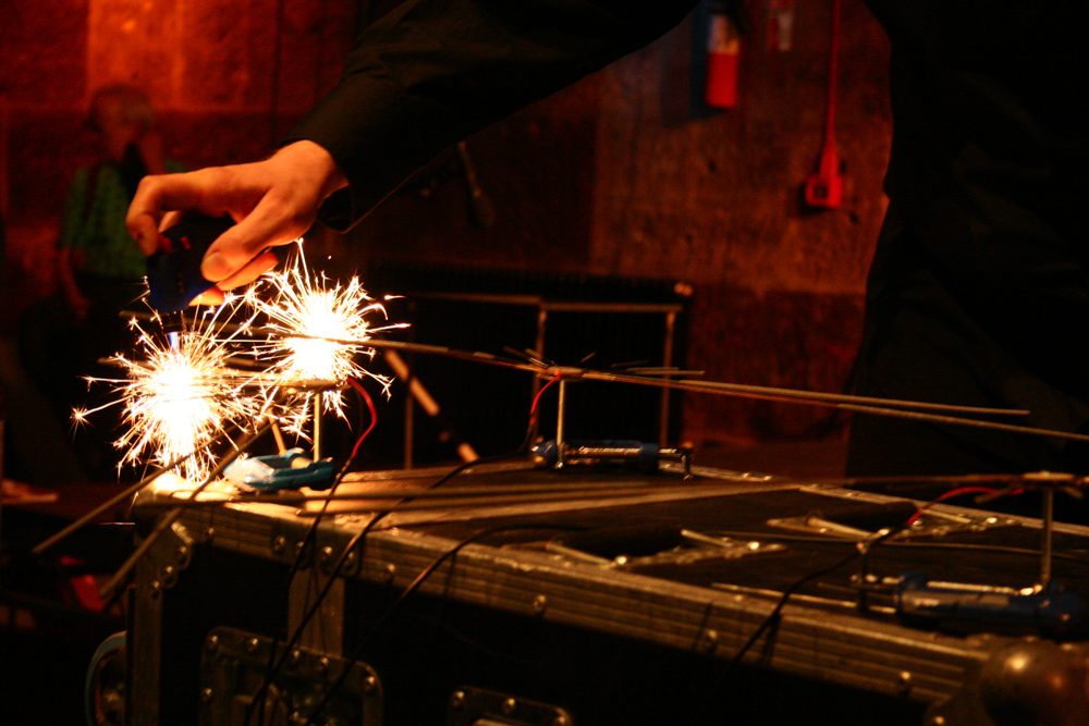 A man's hand near burning sparklers in a darkened railway arch